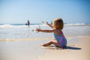 A toddler enjoying the sunny beach while playing with sand, capturing a moment of pure joy and innocence.